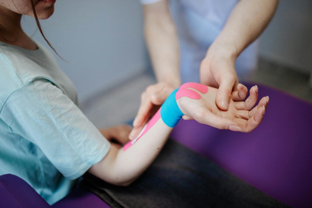 Physiotherapist applying kinesio tape to forearm 