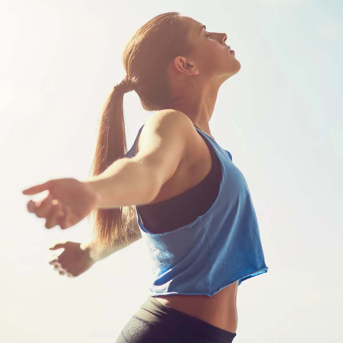 Woman stretching with open arms, expressing pain relief, freedom of movement, and physical well-being in natural light