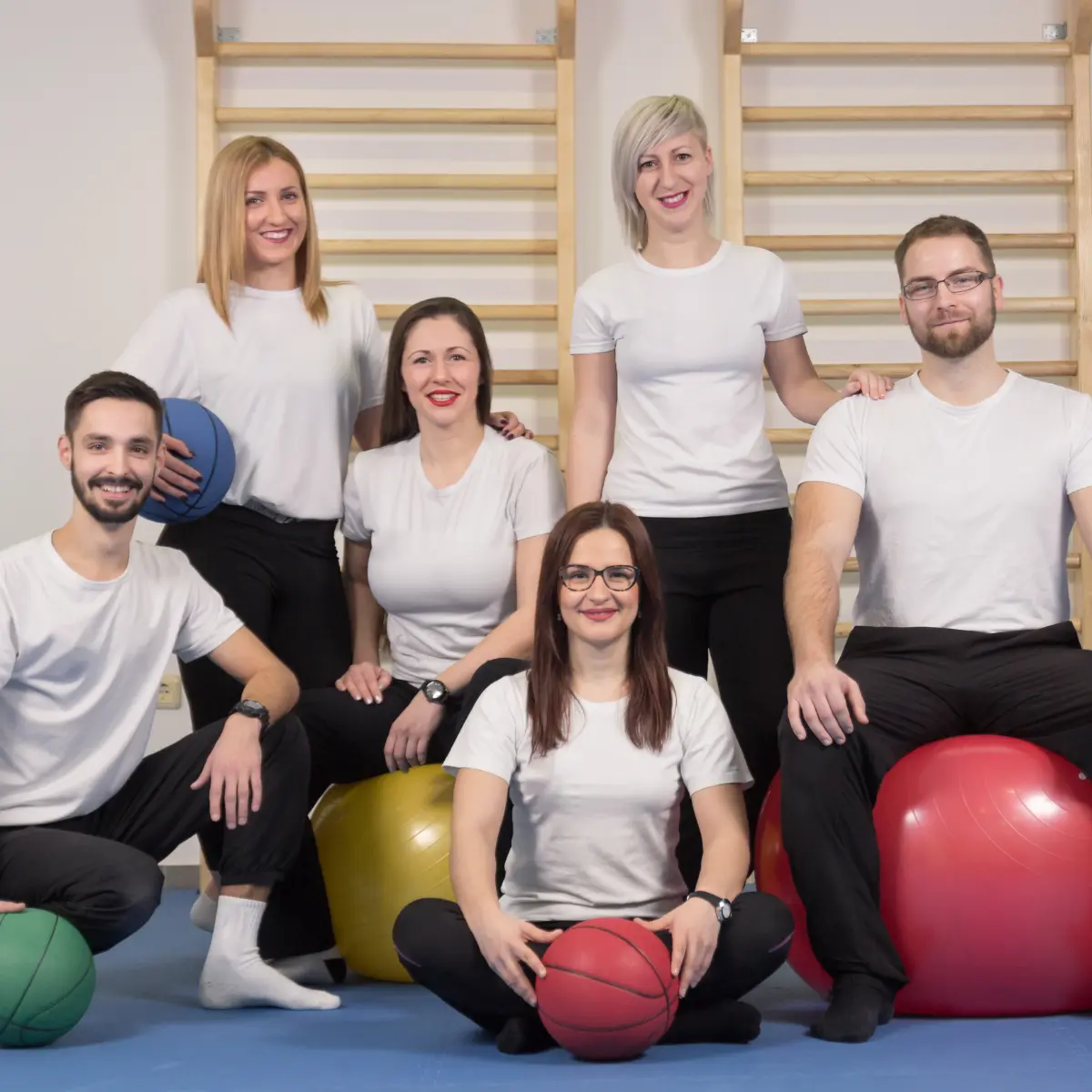 The hips don’t lie Physiotherapy Team in Hamburg Physiotherapy team from hips don’t lie Hamburg sitting in a therapy room with exercise balls and wall bars